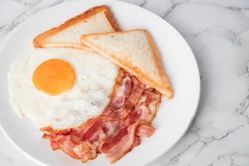 Close up breakfast with sunny side eggs, bacon and toast bread on a plate