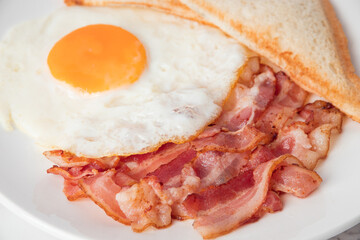 Close up breakfast with sunny side eggs, bacon and toast bread on a plate