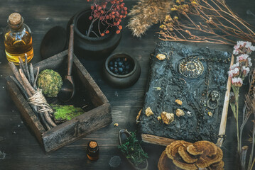 Magic potion bottles, spell book and dried plants on the witch doctor table. Witchcraft.