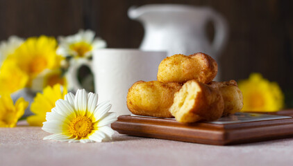 Small sponge biscuits, traditional French madeleines cakes with cup of tea, white and yellow garden flowers on the table. Breakfast or tea time concept