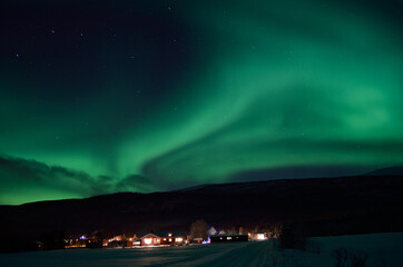 Naklejka na ściany i meble aurora borealis dancing over houses in cold winter