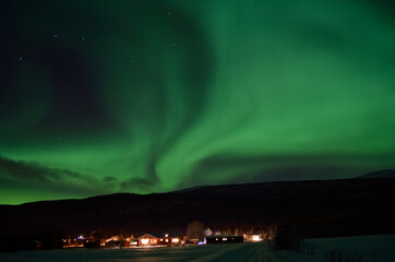 aurora borealis dancing over houses in cold winter