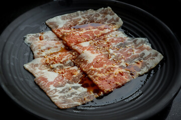 Sliced bacon beef on black dish in japanese restaurant.