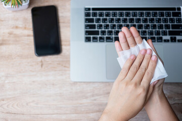 Woman cleaning hands and devices by wet wipes tissue and alcohol disinfectant on workplace during work at home office, protection coronavirus (Covid-19) infection. New Normal and Clean surface concept
