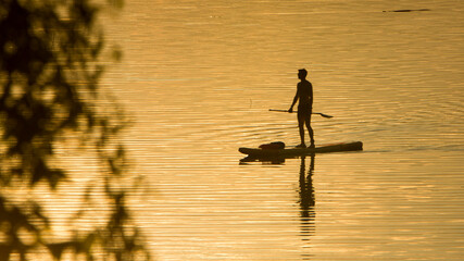 Mężczyzna płynący na łódce na jeziorze w Mucharzu. - obrazy, fototapety, plakaty