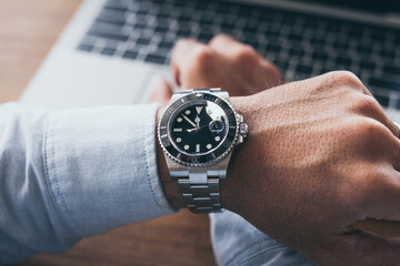 fashionable wearing stylish looking at luxury watch on hand check the time at workplace.concept for...
