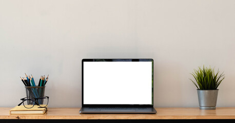 Cropped shot of simple workspace with blank screen laptop, cup, stationery and copy space