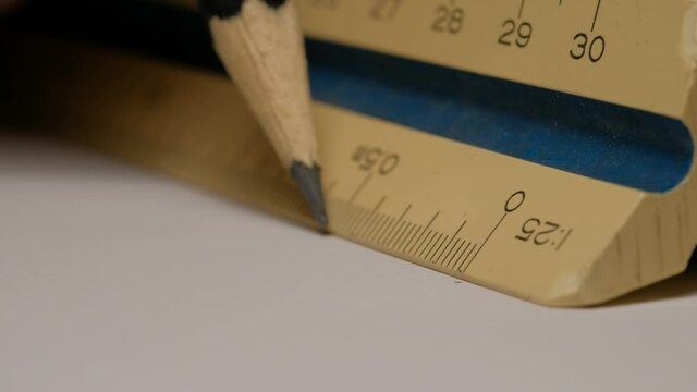 Close up of using a triangular scale ruler with pencil on white paper draw architectural drawings, models. Scale 1:25.