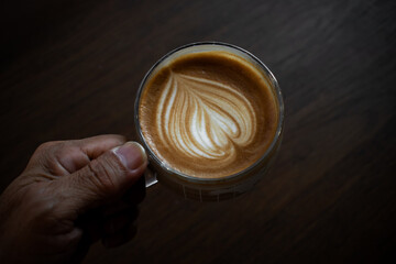 Latte art cup on dark vintage wood table.