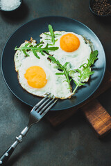Fried egg. Fried egg with herbs on black plate on black background