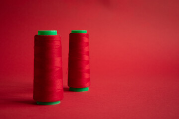 Bobbins on red background. Sew and tailoring concept, sewing tools, needlework.