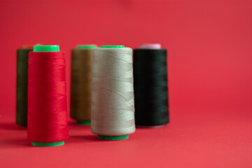Bobbins on red background. Sew and tailoring concept, sewing tools, needlework.
