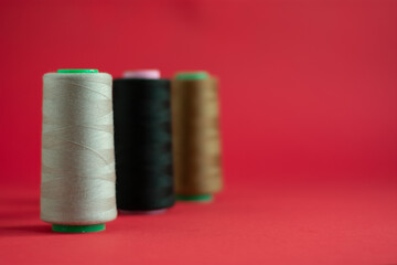 Bobbins on red background. Sew and tailoring concept, sewing tools, needlework.