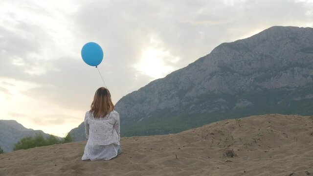 Young woman sitting on the beach with balloon
