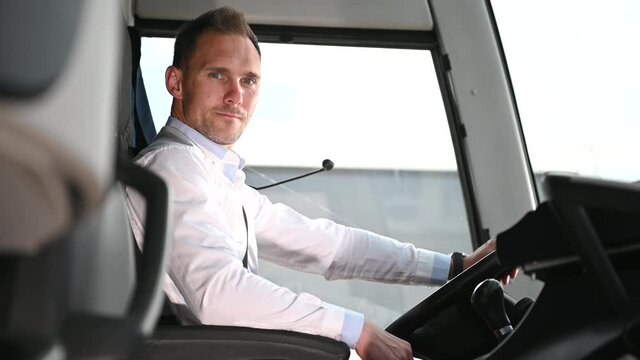 Transportation And Tourism Concept With Male Bus Operator In Driver Seat Looking Attentively At Vehicle Door. 