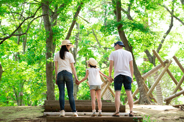 Naklejka na ściany i meble 森の公園で手をつなぐ父と母と娘