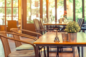 A small bell for calling the waiter and artificial flowers in an aluminum pot placed on a table in a coffee shop.