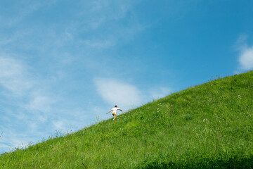 Man feeling happy and free is getting up on the green hill on a sunny day.