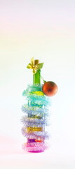 Christmas party a bottle of wine with a Christmas tree toy wrapped in a garland on a light white background. the holiday mood