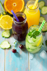 Summer various refreshments drinks. Cherry juice, detox cucumber water and orange juice on blue wooden table. Copy space.