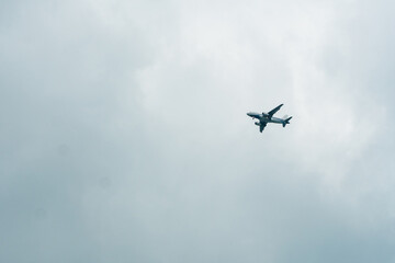 Plane flying in a cloudy sky and preparing to land on a tropical island.