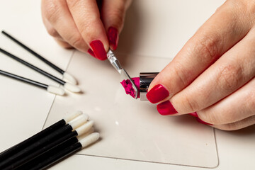 Woman's hands cutting lipstick to apply hygienic makeup on palette and disposable material.