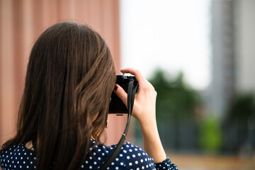 Back view of woman taking photos with vintage camera while sightseeing