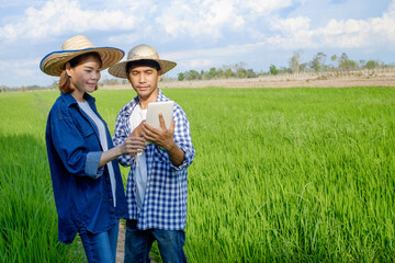 Naklejka na ściany i meble Two asian farmer couple using tablet at green farm