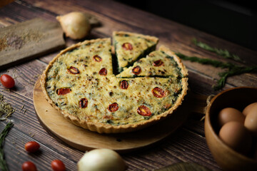 Homemade cheesy spinach quiche for brunch. set on wooden cafe table background.