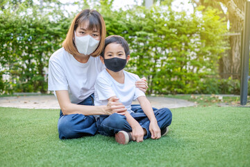 Mother wear face mask with her son wear face mask sitting at home garden. Stay from home concept