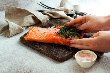 raw fresh piece of salmon on the cutting board with salt ad dill