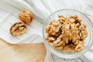 Walnut kernels lie in round bowl on kitchen table, close-up. Healthy lifestyle concept.