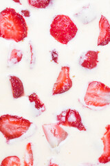filled frame background wallpaper shot of strawberries on the surface of a milky white vanilla cheese cake cream liquid