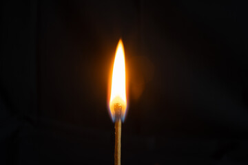 Low key, close up burning matchstick on black background with bokeh