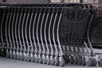 empty metal trolleys, installed one in one in one row, for shopping in stores, hypermarkets, shopping centers.
