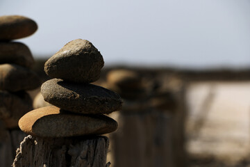 Stacked stones on wooden pillars in the sand of the Camargue in France - Close up