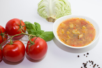 Cabbage and tomato soup with chicken. White background. Next to the ingredients