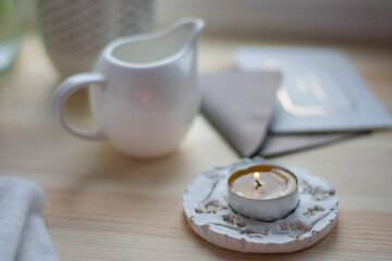 Coffee at home, comfort at home. Milk jug,  mug, candlestick, candle, envelope and postcard on wooden desk. White color. Still life a cozy coffee.