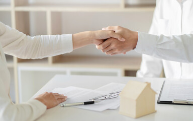 Real estate agent hand shaking with customer for house contract agreement.