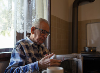 Old man reading newspaper at home