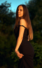 Beautiful girl on the nature near the green shore. Enjoys the setting sun. The concept of outdoor...