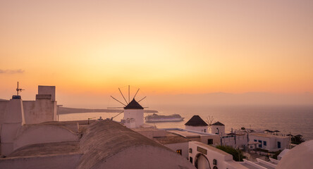 Fototapeta na wymiar Windmill and cruise ship at sunset in Oia, Santorini Island, Cyclades, Greece 