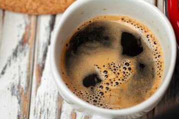 White cup of coffee on wooden kitchen table