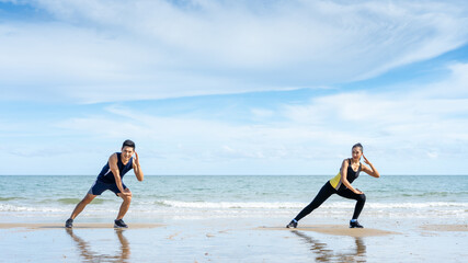 Fototapeta na wymiar Asian couples leave some distancing between exercising or stretching before exercising in the morning by the sea.