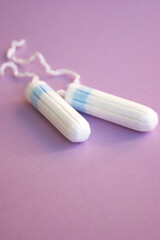 Menstrual pads and tampons on menstruation period calendar with on lilac background.