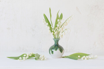 lily of the valley in little vase on background old white wall