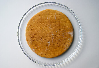 Round baked cake layer on a plate. Homemade cooking honey cake.