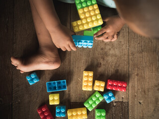Top view Dark-skinned Asian children are playing blocks at the wooden floor. Learning and development of children