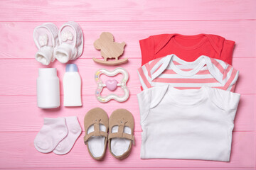 Baby clothes with toys on a pink background. Flat lay