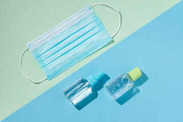 Blue surgical face mask, antibacterial gel and alcohol spray to prevent contagion of corona. Blue and green background